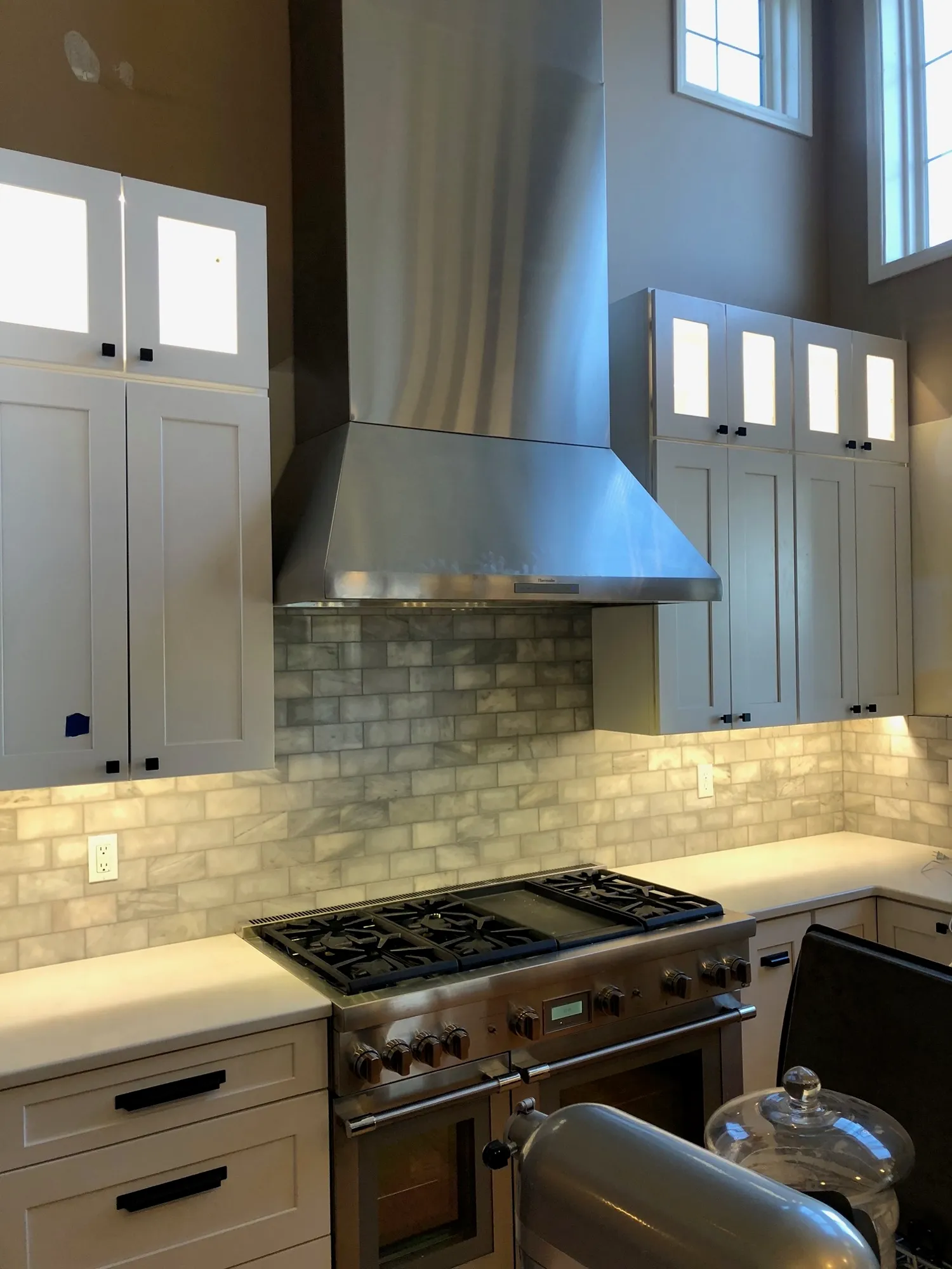 Carrara marble subway tile backsplash behind a stainless range hood