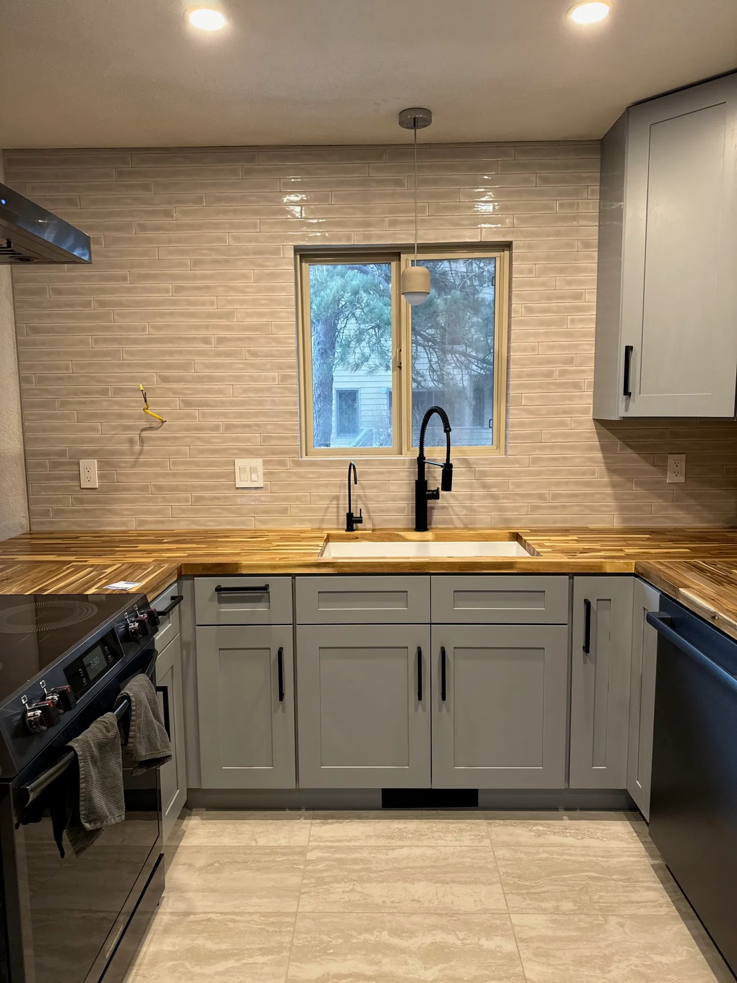 Cream linear tile backsplash above butcher-block countertops