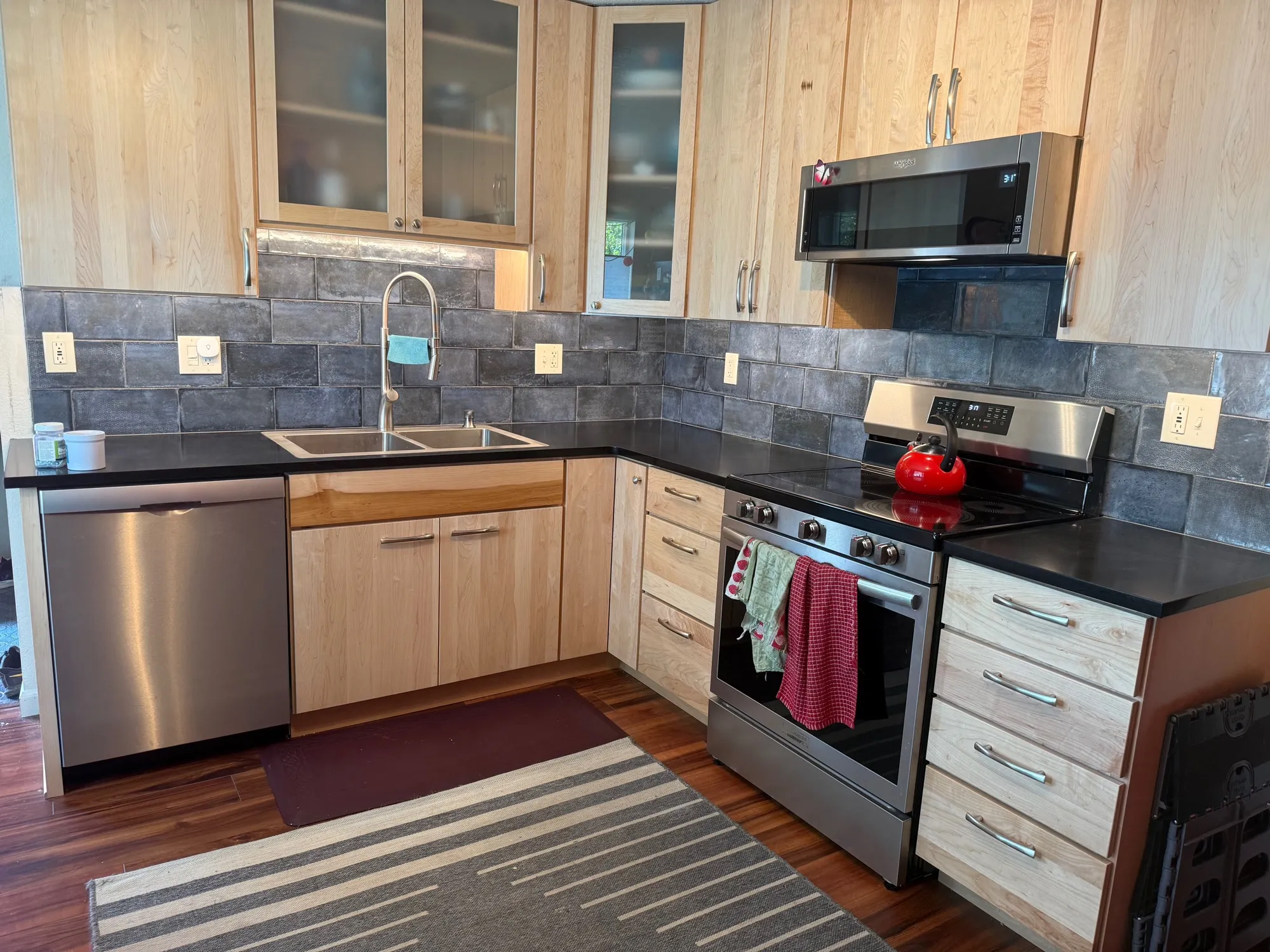 Gray slate subway tile backsplash with light wood cabinets and black countertops