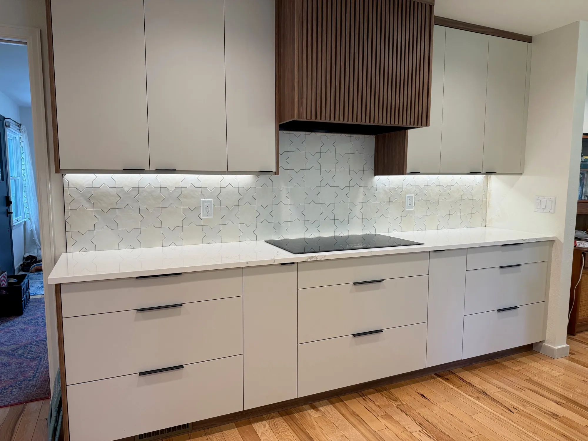 White star-and-cross Moroccan tile backsplash with a wood-slat range hood